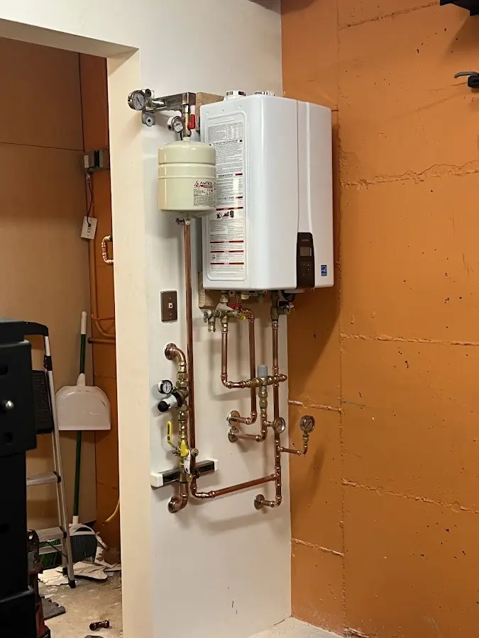 Plumbing technician inspecting water heater connections in East Greenville